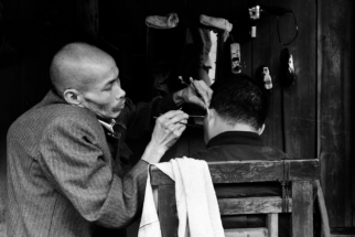 A hunchback cleans a mans ears in a Chinese teahouse