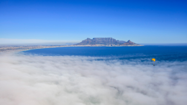 A brave paraglider floats over a misty Cape Town Ocean 