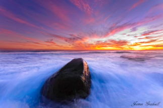 Seascape image single rock with sunset and silky water