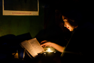 Portrait of Chinese woman reading by candlelight